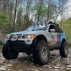 an off - road vehicle is parked on the side of a rocky trail with trees in the background