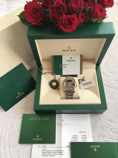 a rolex watch in a green box with red roses