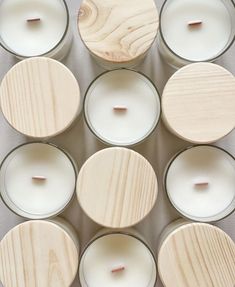 twelve candles with wooden lids are arranged in a grid on the floor, one is empty