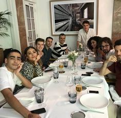 a group of people sitting around a table with plates and glasses on it, posing for the camera