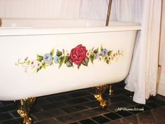 a bathtub with roses painted on the side and gold legs, in a bathroom