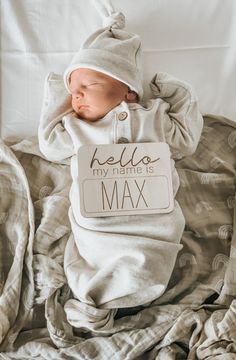 a baby is sleeping on a bed wearing a bib that says hello my name is max