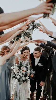 a group of people standing next to each other with their hands in the air and holding flowers