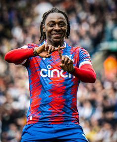 a man with dreadlocks standing in front of a crowd at a soccer game