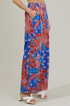 The Amazonia Blue Floral Mulvane Wide Leg Pants are here to show you keep you relaxed and in style! It shapes a high waist with a hidden zip fly and top button closure. It also has a stretchy waist on the back and pockets on each side. Pair this up with the matching top to complete the look!- Side pockets- High waist- Wide leg- Hook and clasp- Color: Blue RedSize + Fit - Model is 5'8" and wearing size XS- Measurements taken from size S - Waist: 14"- Inseam: 30 1/2" Fabric Self:100%Cotton Style N Spring Blue Wide Leg Pants, Blue Wide Leg Pants With Elastic Waistband For Summer, Loosely Fitted Versatile Blue Bottoms, Blue Trousers For The Beach, Versatile Loosely Fitted Blue Bottoms, Blue Wide Leg Pants For Beach With Pockets, Blue Wide Leg Beach Pants With Pockets, Summer Wide Leg Blue Pants, Blue Wide-leg Pants For Summer