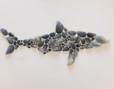 a fish made out of shells is hanging on the wall