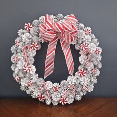 a christmas wreath made out of pine cones and candy canes on a wooden table