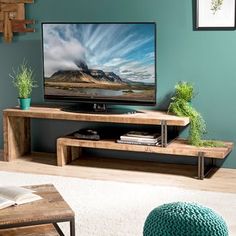 a flat screen tv sitting on top of a wooden stand in front of a green wall