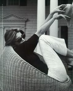 a woman laying on top of a wicker chair