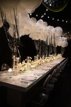 a long table with many white balloons hanging from the ceiling