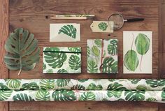 green leaves and papers laid out on a wooden table next to a pair of scissors