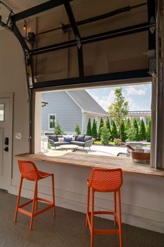 two orange chairs sitting on top of a counter in front of a window with an open door