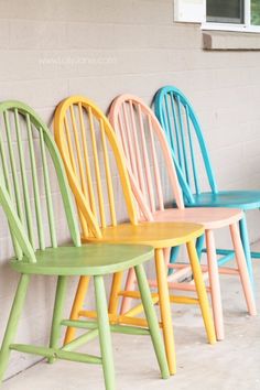 four colorful chairs lined up against a wall