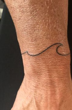 a man's wrist with a wave tattoo on it