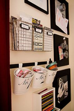 three buckets are hanging on the wall next to some pictures and pencils in bins