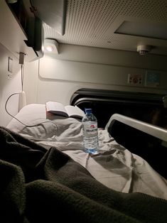 a bottle of water sitting on top of a bed next to a pillow and blanket