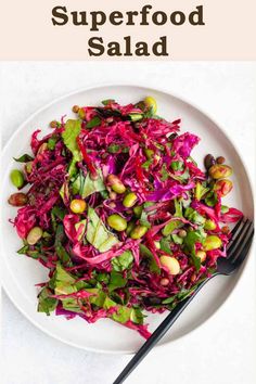 a white plate topped with red cabbage and pistachios next to a fork