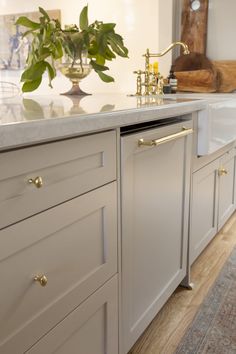 a kitchen with white cabinets and gold pulls on the handles, brass knobs, and a marble counter top