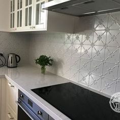 a kitchen with white cabinets and black counter tops is pictured in this image, there is a potted plant on the stove