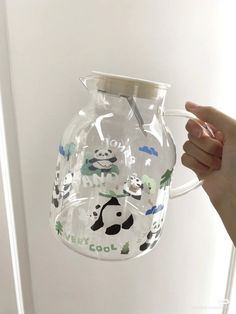 someone is holding a clear glass pitcher with animals on it and the bottom has a white handle