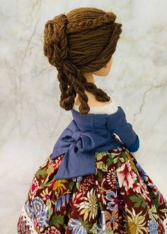 the doll is wearing a dress with flowers on it and braids in her hair