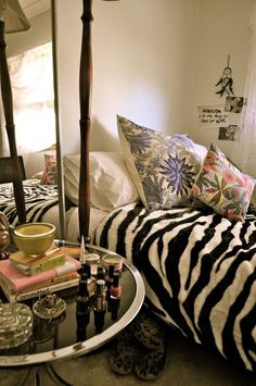 a bedroom with zebra print bedding and accessories on the table in front of it