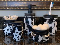 three jars with toothbrushes and soap in them sitting on a granite counter top