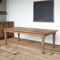 a wooden table sitting on top of a hard wood floor next to a chalkboard