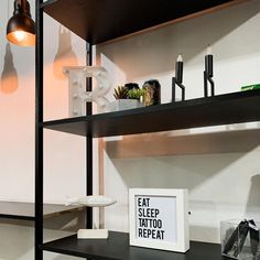 a shelf that has some items on it and a sign in front of it reading eat sleep tattoo repeat