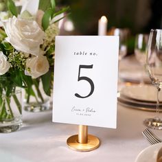 the table numbers are placed on top of each other in front of white flowers and candles