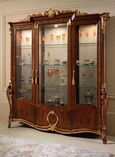 an ornate display case with glass doors and gold trimmings on the top shelf