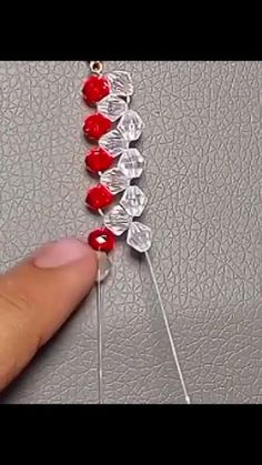 someone is stitching together red beads on a piece of string