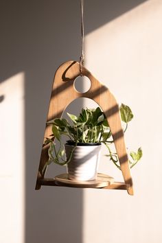 a wooden plant hanger with a potted plant in it on a shelf next to a wall