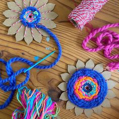 several different colored yarns and flowers on a wooden table with scissors, thread, and twine