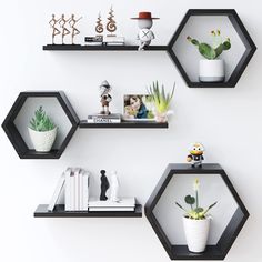 three black hexagonal shelves with plants and books on them, each holding photos