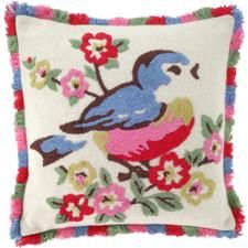 an embroidered pillow with a blue bird on it and pink flowers in the center, sitting on a white surface