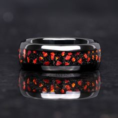 a wedding band with red and black flowers on the inside is shown in front of a reflective surface