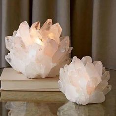 two crystal rocks sitting on top of a table next to a book and window curtain