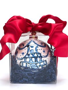 a glass ornament with a red ribbon around it