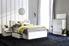 a white bed sitting in a bedroom next to a dresser and mirror on a wall