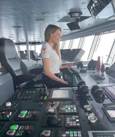 a woman is sitting in the control room of a ship looking at her cell phone