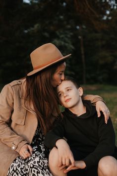 a woman sitting next to a young boy wearing a brown hat and black shirt,