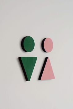 two geometric shapes on a white surface, one is pink and the other is green