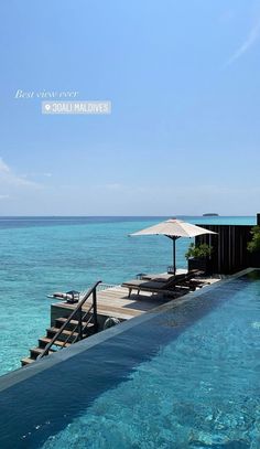 an outdoor swimming pool with lounge chairs and umbrellas on the side, overlooking the ocean