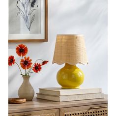 a yellow lamp sitting on top of a table next to a vase filled with flowers