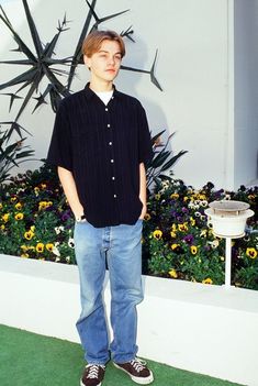 a young man standing in front of a flower garden