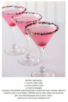 two martini glasses with pink liquid and sprinkles on them, sitting next to each other