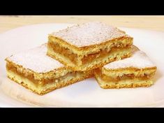 four pieces of dessert sitting on top of a white plate covered in powdered sugar