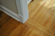 an open door on the side of a wooden floor with hard wood floors and white trim