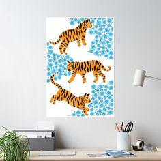 two tigers running across a blue and white flowered background on a wall above a desk